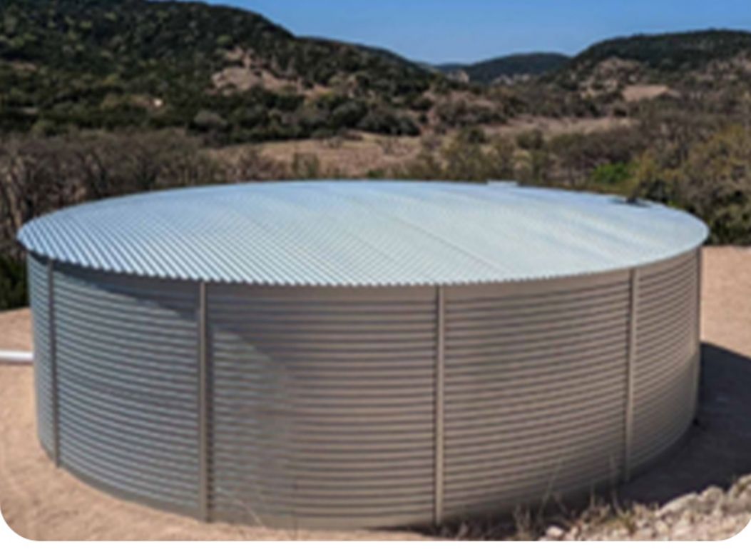 A galvanized metal water storage tank installed by TR Drilling on a Texas Hill Country ridge